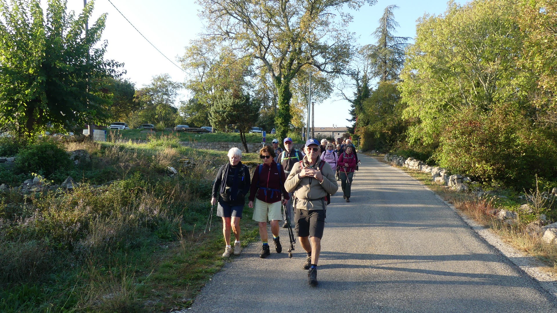 Départ en groupe sur la route, bâtons de marche en main